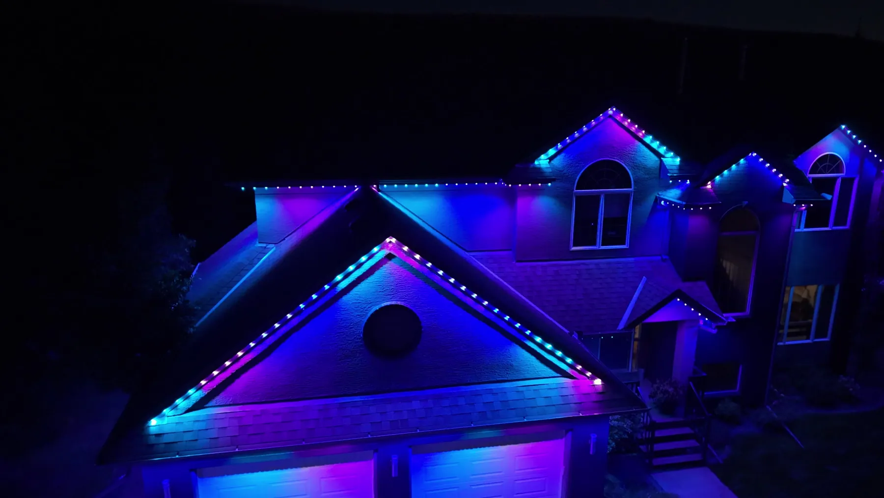 Gables lit in blue and violet against the night sky.